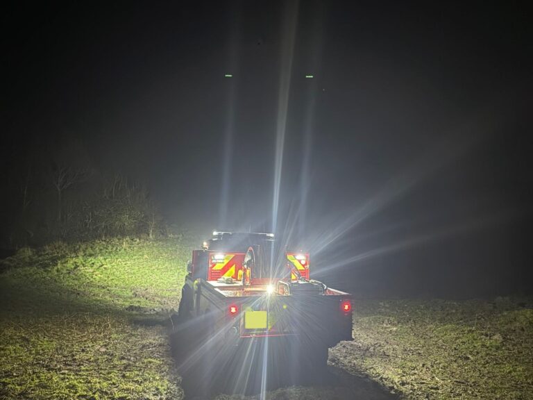 A fire service Land Rover sits on an area of Butser Hill during a nighttime rescue. The vehicle has its flood lights in use, highlighting how dark the area is.