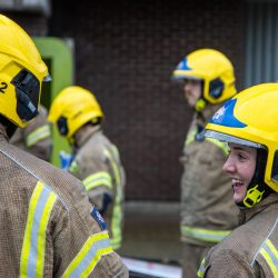 Group of six trainee firefighters at training candid shot - one on the right and close to camera is side profile and smiling the others features are not clearly visible