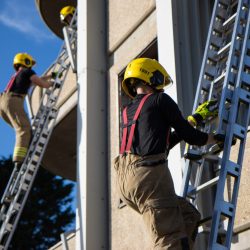 Two trainee firefighters doing a ladder climb up training tower