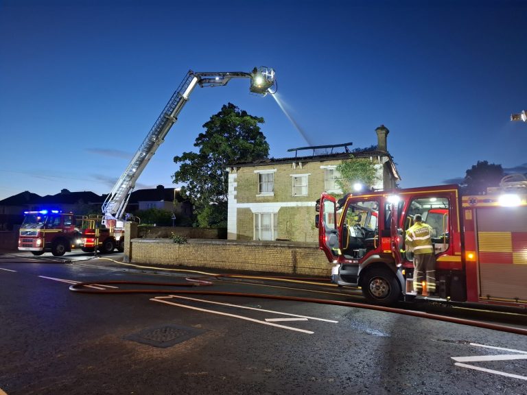 Fire engine and crews on scene at a house fire at night