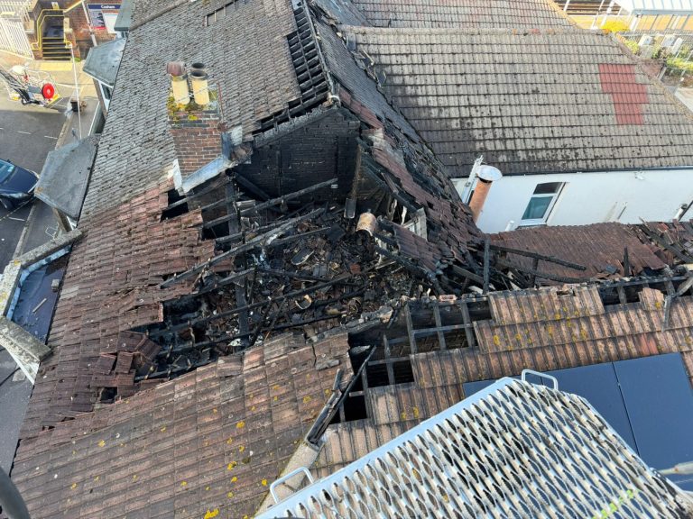 Photo taken from our aerial ladder platform vehicle, which is looking down on the fire damage to the flat's roof. Charred remains of the roof structure show under missing tiles.